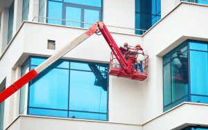 Professional team of decorators on a cherry picker painting a commercial building