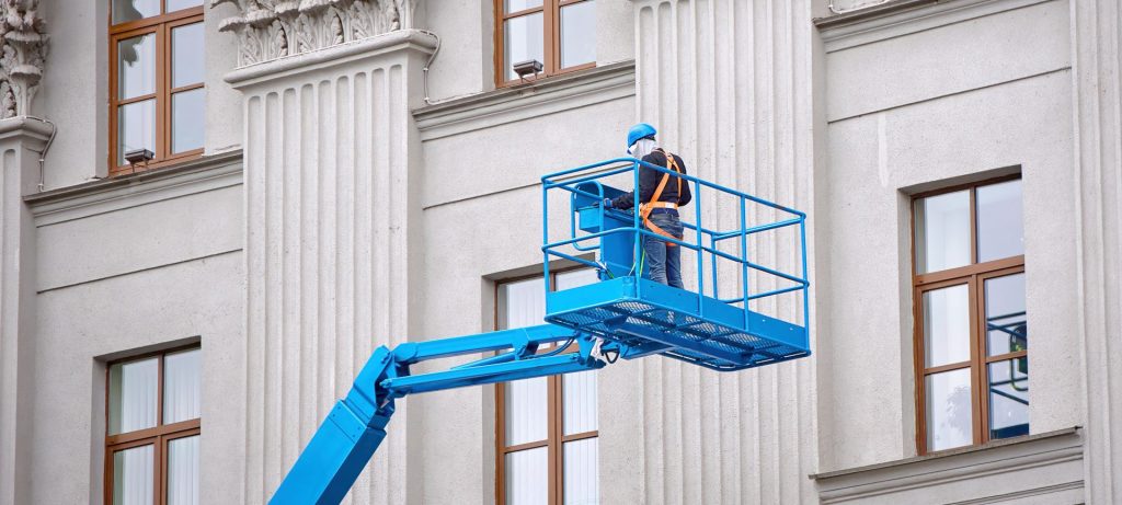 Painting building on a blue cherry picker