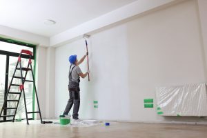 Man using long paint roller on interior walls