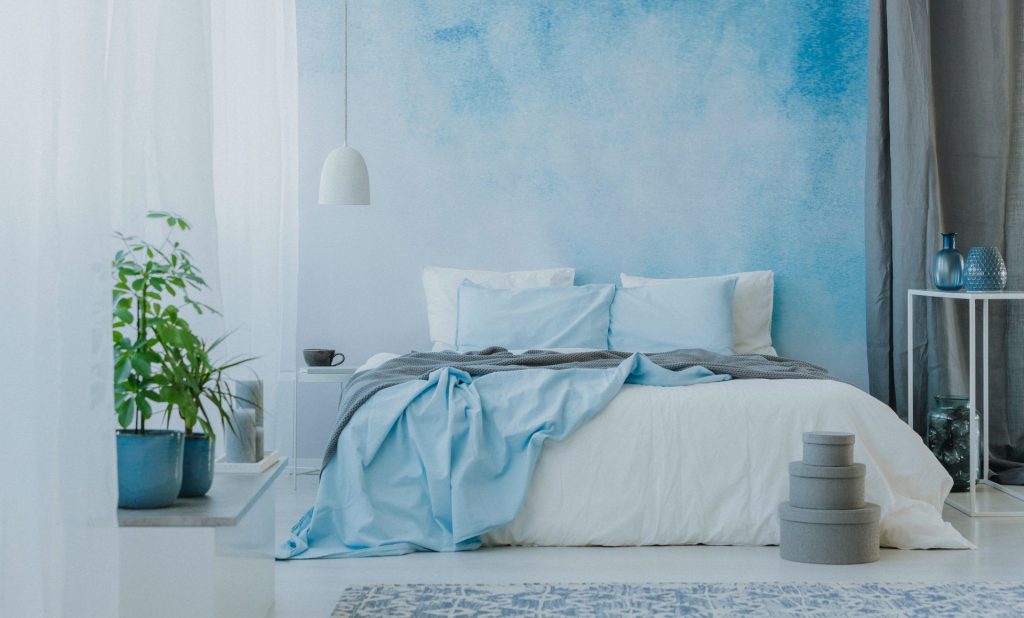 Bedroom with comfy bed against a blue ombre wallpaper design